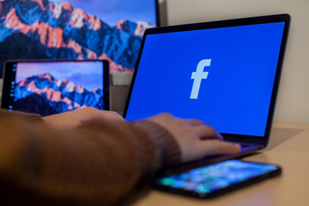 Una persona está usando una computadora portátil para diseño web con el logotipo de Facebook.